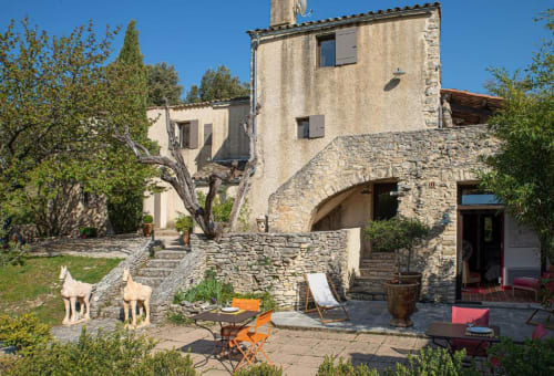 La cour du Clos des Amandiers à Simiane-la-Rotonde : bâtisses en pierre, olivier noueux et mobilier de détente