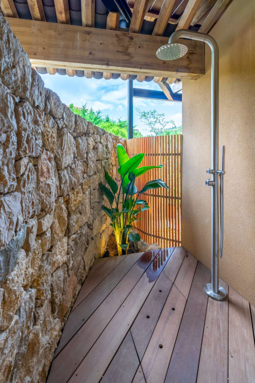 Douche extérieure à la Villa Solviou, Lord Resort, avec mur en pierre, terrasse en bois et plante tropicale à Six-Fours, France