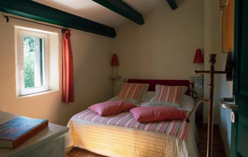 Chambre lumineuse au Clos des Amandiers à Simiane-la-Rotonde avec lits rayés, accents rouges et poutres apparentes