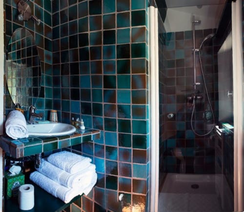 Salle de bains Studio Tournesol au Clos des Amandiers avec carrelage turquoise, lavabo, serviettes et douche à Simiane-la-Rotonde
