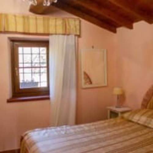 Camera accogliente presso Antico Belvedere B&B con muri in terracotta, travi in legno, letto e finestra con tende