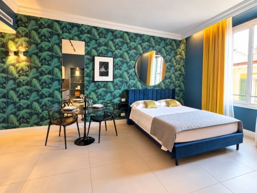 Suite moderna del Seven Suites Sanremo con carta da parati tropicale, letto blu, tende gialle e zona pranzo