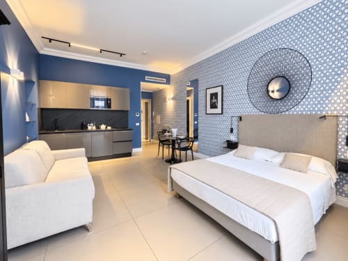 Moderna suite presso Seven Suites Sanremo con letto, cucina, zona living e carta da parati con motivi blu