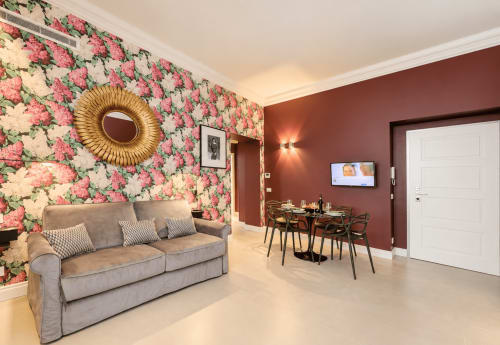 Suite moderna a Seven Suites Sanremo con carta da parati floreale, divano grigio, zona pranzo e parete accent in terracotta