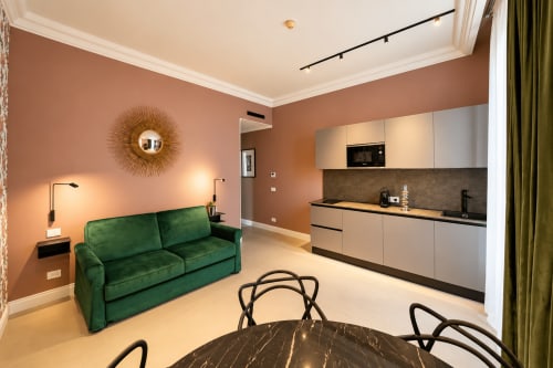 Suite moderna a Seven Suites Sanremo con divano verde, pareti in terracotta e cucina integrata