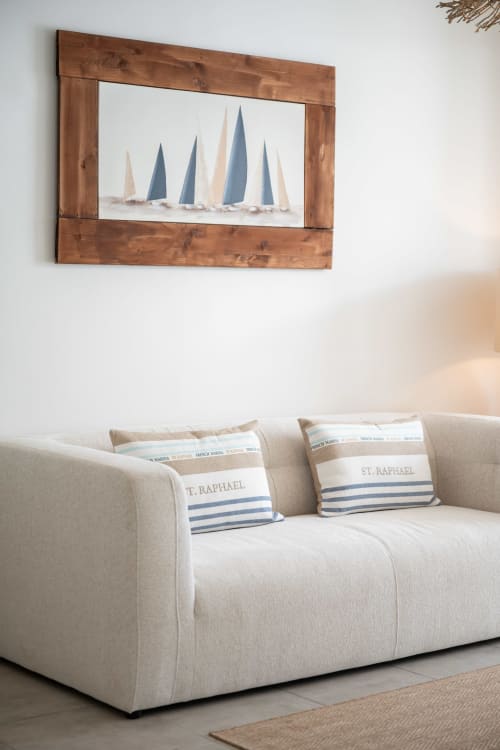 Cream sofa with nautical pillows beneath framed sailboat artwork in Vista Del Mar apartment, Guadeloupe