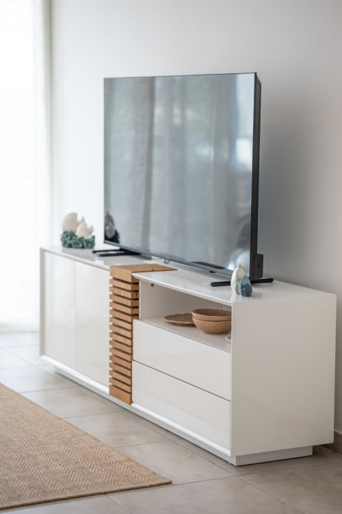 Modern white TV stand with wooden accent panel in Vista Del Mar apartment, Guadeloupe