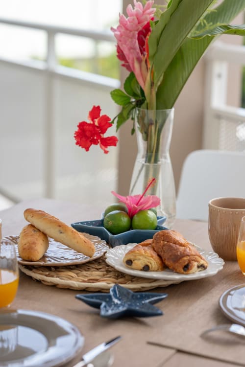Breakfast spread at Vista Del Mar with tropical flowers, pastries, fresh limes, and coffee overlooking Guadeloupe