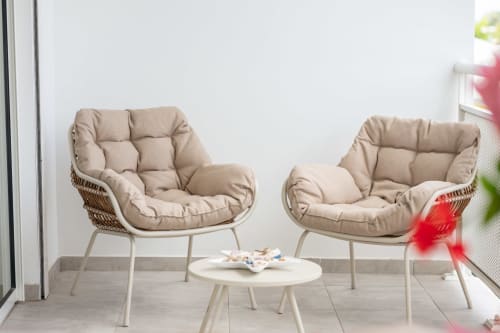 Two beige cushioned outdoor chairs with small table on terrace at Vista Del Mar Guadeloupe apartment