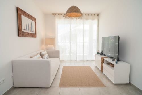 Modern apartment living room at Vista Del Mar, Guadeloupe with cream sofa, TV, natural lighting, and coastal-inspired décor