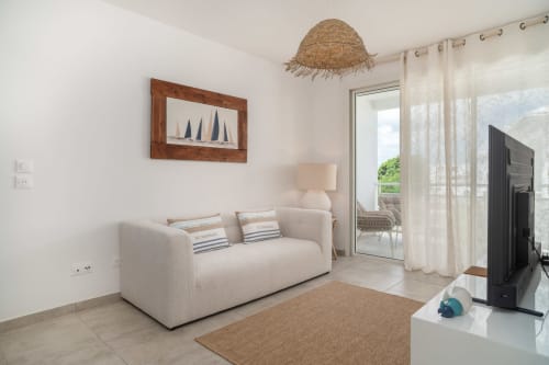 Bright living room with beige sofa, straw pendant light, and terrace access at Vista Del Mar, Guadeloupe
