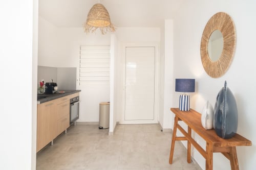 Modern apartment kitchen and living area at Vista Del Mar, Guadeloupe with wooden cabinetry, straw pendant light, and coastal