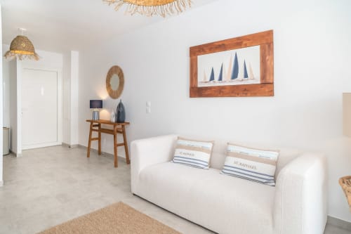 Bright, modern Gissac apartment in Sainte-Anne, Guadeloupe with white sofa, wooden decor, and nautical artwork