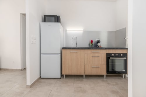 Modern kitchen in Vista Del Mar apartment, Guadeloupe with wood cabinets, black countertop, white refrigerator, and built-in