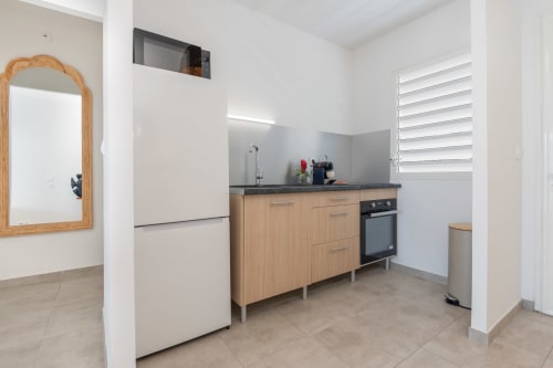 Modern kitchen in Vista Del Mar apartment, Sainte-Anne Guadeloupe, with wooden cabinets, black countertop, stove, and