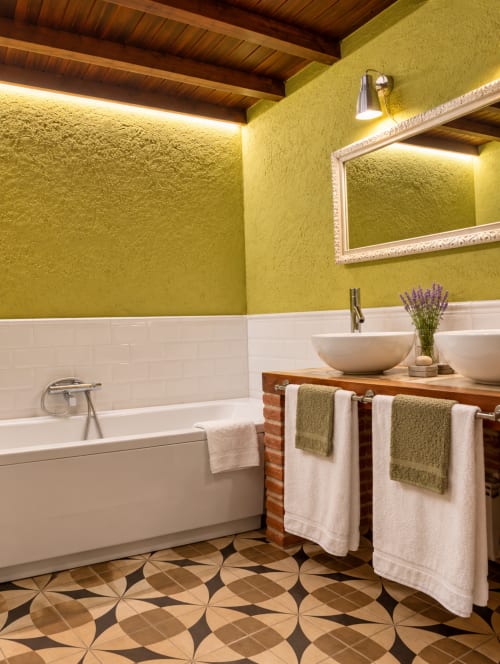 Baño de lujo con paredes verde chartreuse, azulejos blancos tipo metro, techo de madera, toallero climatizado y piso geométrico en El