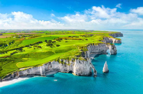 Les falaises blanches spectaculaires d'Étretat, ses eaux turquoise et formations rocheuses emblématiques avec littoral verdoyant.