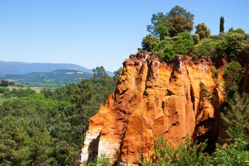 Formation rocheuse rouge avec arbres verts dominant la vallée près de Simiane-la-Rotonde, France