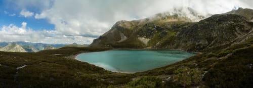 Lago alpino turquesa rodeado de montañas rocosas y vegetación verde cerca de Cofiñal, España
