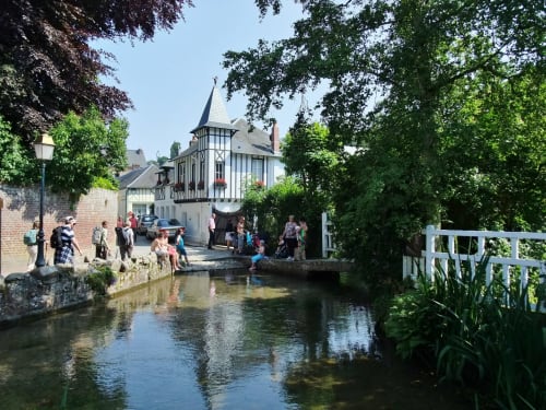 Historic half-timbered building by canal in Saint-Valery-en-Caux with visitors enjoying the charming Norman architecture