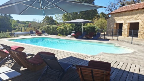 Piscine avec terrasse en bois et chaises longues aux Gîtes Le Pech, Sainte-Foy-de-Longas, France