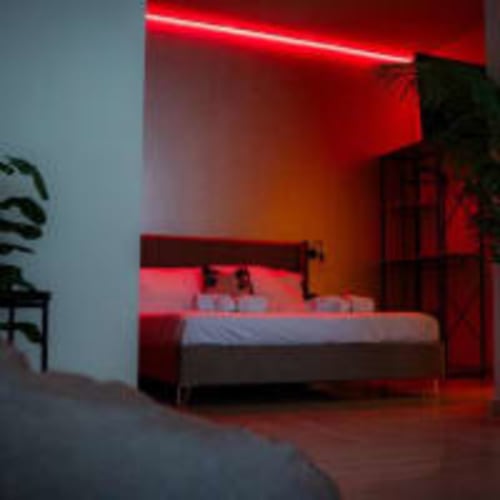 Camera moderna a Moon Rooms By Celeste di Catania con illuminazione al neon rosso, letto e vista sulla città