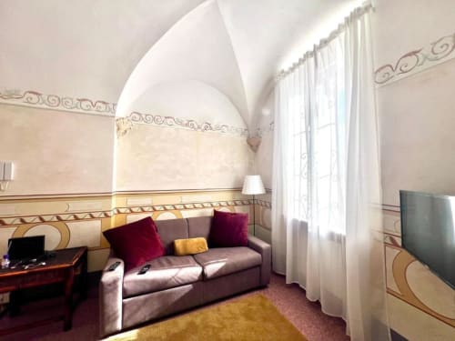 Suite elegante alle SEVEN SUITES SANREMO con soffitto a volta, divano viola, carta da parati decorativa e finestre luminose