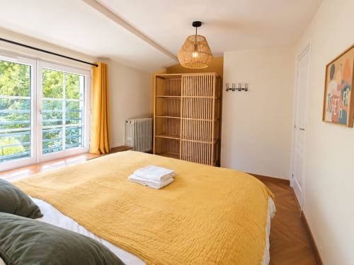 Chambre lumineuse du gîte Maison Héléna avec literie jaune, étagères en bois et vue sur la campagne de Lain