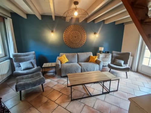 Modern living room at Gîtes Le Pech cottage with gray sofa, armchairs, wooden coffee table, and teal accent wall with