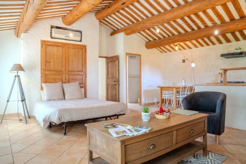Studio spacieux aux Les gîtes de Val avec poutres apparentes, mobilier bois, canapé-lit futon et vue sur le jardin à Cabannes.