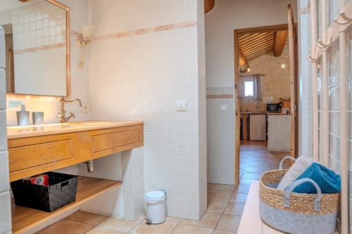 Salle de bain spacieuse du gîte Sous les Étoiles aux gîtes de Val, Cabannes, avec meuble vasque en bois, carrelage blanc