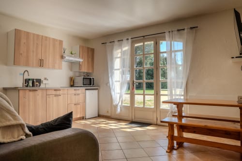Kitchenette lumineuse et coin séjour aux gîtes de Val à Cabannes, vue sur jardin par les portes-fenêtres