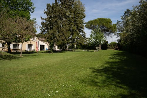 Vaste pelouse entourant le gîte Au Coin du Feu aux Gîtes de Val à Cabannes, avec arbres matures et vue sur le jardin