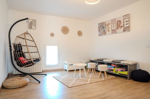Salle de jeux moderne de la chambre d'hôtes Nature à Cabannes avec chaise suspendue, table en bois, paniers tressés et jeux à disposition