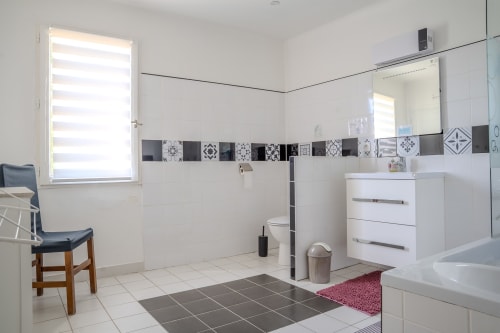 Salle de bains moderne aux gîtes de Val à Cabannes : vasque blanche, toilettes, baignoire et finitions carrelage décoratives