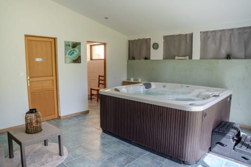 Espace bien-être aux Gîtes de Val avec bain à remous, portes en bois et vue sur le jardin à Cabannes