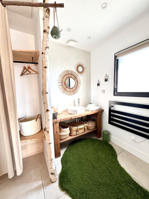 Luxury bathroom at Maison Florence Ivakno with wooden vanity, sunburst mirrors, green rug, and modern amenities