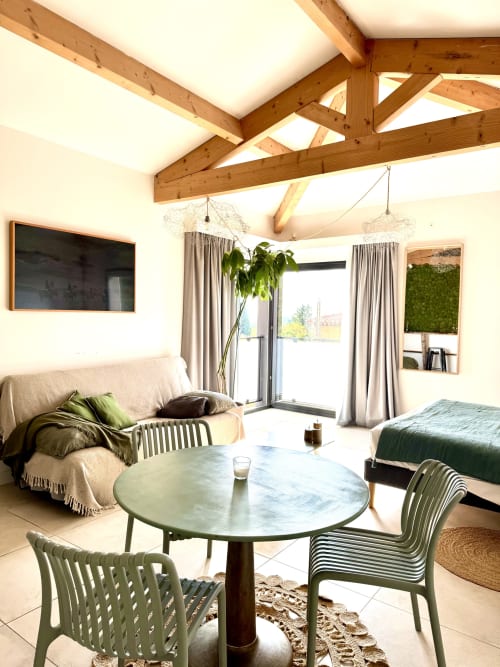 Luxury suite at Maison Florence Ivakno with exposed beams, green chairs, round table, sofa, bed, and glass doors opening to