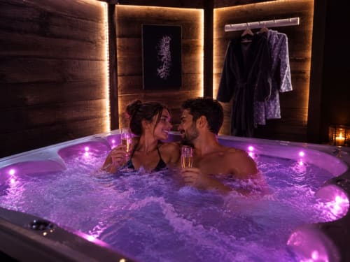 Couple savourant le champagne dans un jacuzzi illuminé en violet à la villa Les Villas Aux Portes De L'océan à Biscarrosse