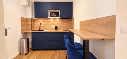 Kitchenette moderne avec armoires bleu marine, plan de travail en bois et coin repas à l'hôtel NN Patrimoine de Douvaine