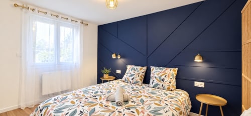 Chambre moderne de NN Patrimoine à Douvaine avec mur d'accent géométrique bleu marine, literie florale et luminaires dorés