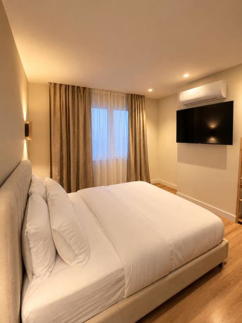 Moderna habitación doble en Tinto Dreams Hostel de Haro con ropa de cama blanca, TV, aire acondicionado y puertas al balcón con cortinas
