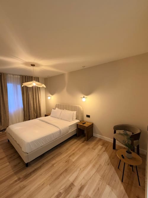 Dormitorio moderno en el Hostal Tinto Dreams de Haro con cama blanca, lámparas colgantes, muebles de madera y decoración cálida