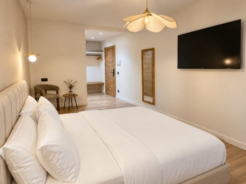 Moderna habitación doble en Tinto Dreams Hostel de Haro con cama blanca, TV, iluminación colgante y baño privado