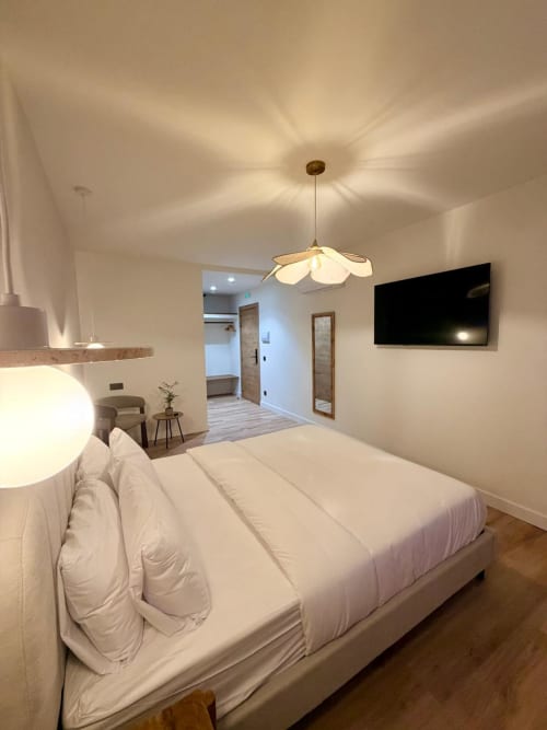 Moderna habitación de hotel en Tinto Dreams Hostel de Haro con ropa de cama blanca, lámpara colgante, televisor y acceso a baño privado