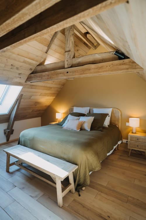 Cozy loft bedroom at Le Clos d'Omaha with exposed wooden beams, queen bed, and warm lighting