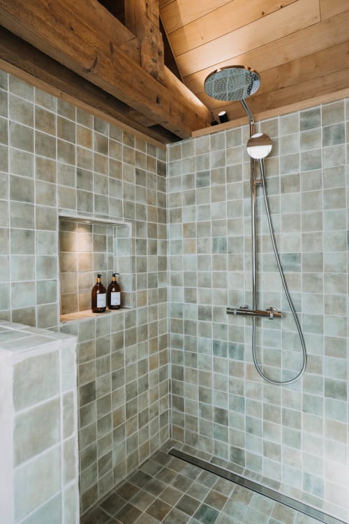 Luxury shower with green tiled walls and overhead rain showerhead at Le Clos d'Omaha suite