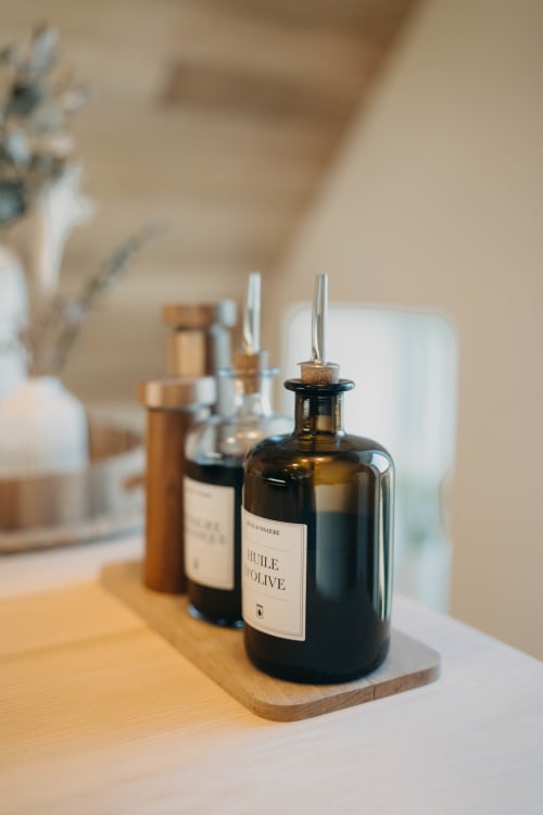 Olive oil bottles with pour spouts on wooden board in Suite Lushoto at Le Clos d'Omaha hotel