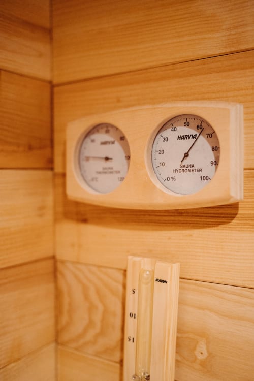 Harvia sauna hygrometer and thermometer mounted on wooden wall in Suite Lushoto at Le Clos d'Omaha