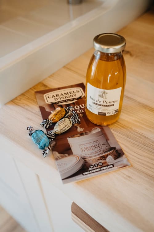 French caramels, apple juice bottle, and candies arranged on wooden table at Le Clos d'Omaha hotel